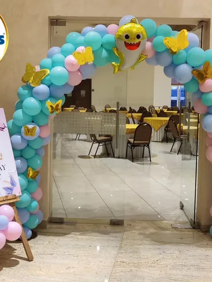 A welcoming entrance for a Baby Shark-themed party, featuring a blue and pink balloon arch topped with a Baby Shark foil balloon.