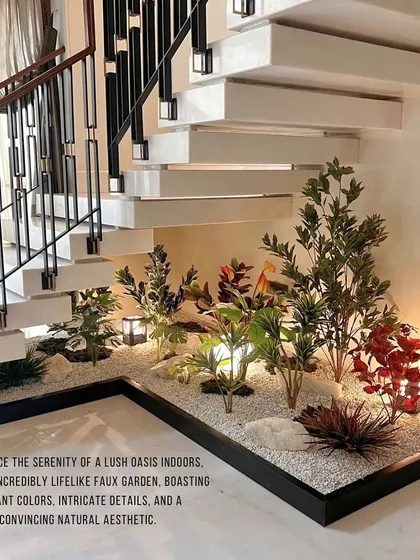This under-staircase garden demonstrates a different aesthetic, using a variety of colorful faux plants set in a bed of white pebbles. The design incorporates subtle lighting to highlight the textures and create a warm, inviting atmosphere.