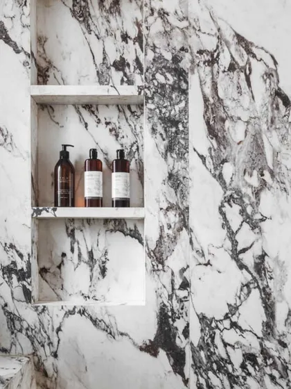 We see bathrooms as an opportunity for a little indulgence. For this terrace bathroom, I selected a dramatic marble with bold, graphic veining to create a statement wall. The result is a space that feels like a private spa, turning a functional room into a luxurious escape.