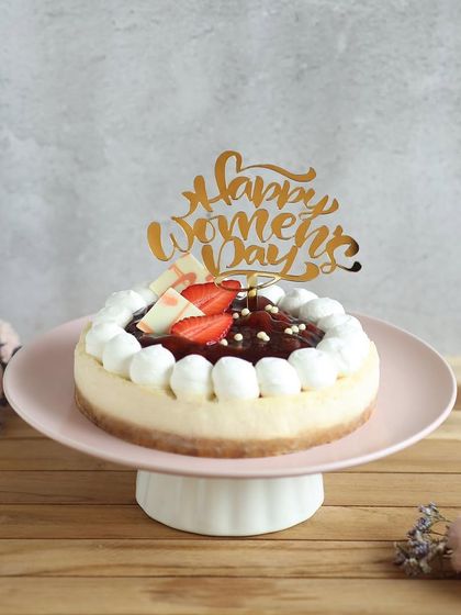 A beautiful strawberry cheesecake with a "Happy Women's Day" topper, a light and fruity way to celebrate the amazing women in your life.