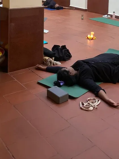 A view of participants in a reclined butterfly pose during a workshop. Using props like blocks and pillows helps the body to relax and the hips to open gently.