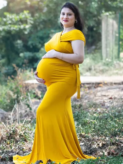 A side profile that beautifully accentuates the baby bump. The fitted yellow gown and the natural outdoor light highlight the amazing transformation of pregnancy.