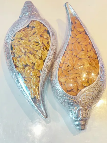 An overhead view of the shell-shaped silver bowls, showcasing the quality of the walnuts and almonds inside.