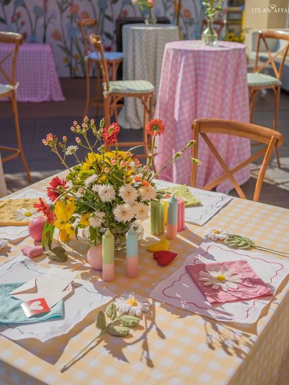 A close-up of a picnic table, set with colorful candles, fresh wildflowers, and whimsical, handcrafted details.