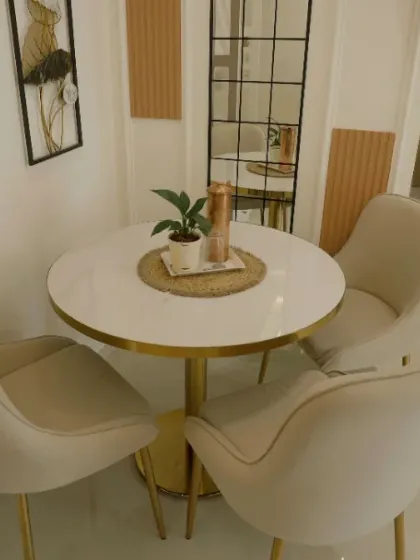 A chic and compact dining setup with plush cream chairs and a gold-accented table, perfect for intimate meals.