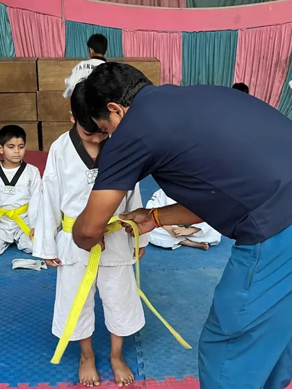 The journey begins with the first belt. Here I am tying a yellow belt on a young student, marking the first step in their Taekwondo journey.