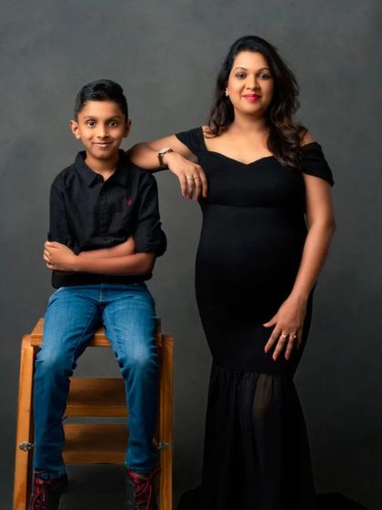 A stylish portrait of a mom-to-be and her son, both dressed in classic black.