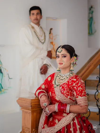 A classic portrait of the couple on the stairs, showcasing the bride's regal attire and the groom's quiet presence.