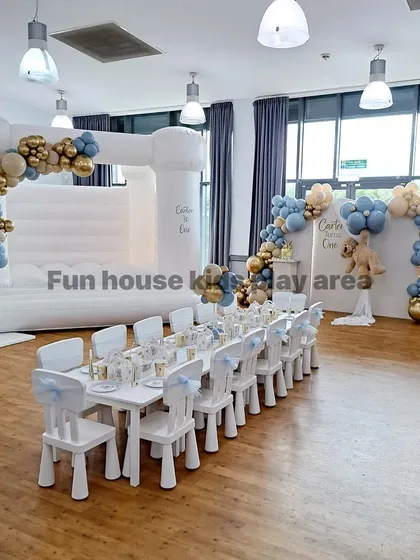 This wide shot shows a complete indoor party package. Our white tables and chairs are paired with a matching white bouncy castle, creating a cohesive and stylish look for this celebration.
