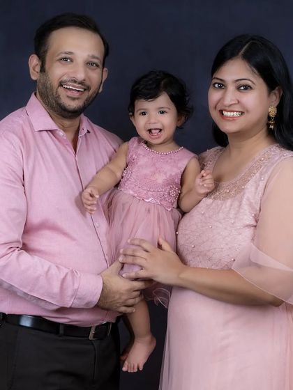 A close-up of a happy family, with their daughter's joyful expression at the center. The coordinated pink outfits add to the warmth of the portrait.