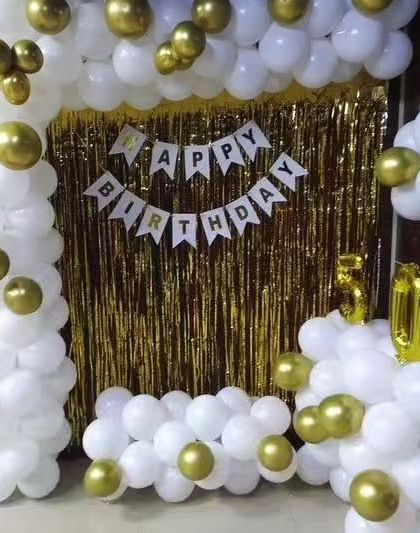 An elegant white and gold balloon arch against a gold shimmer curtain, creating a classic and glamorous birthday photo corner.