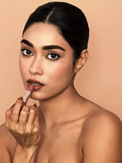 A classic beauty shot demonstrating product application. The clean, neutral background keeps the focus entirely on the model and the cosmetic product.