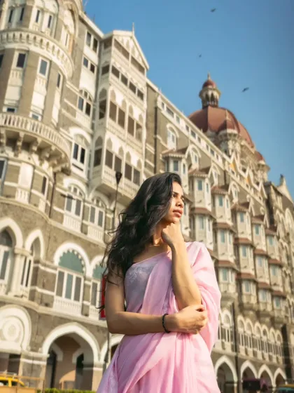 A low-angle shot that makes both the model and the building behind her look majestic. The birds in the sky add a touch of life and movement.