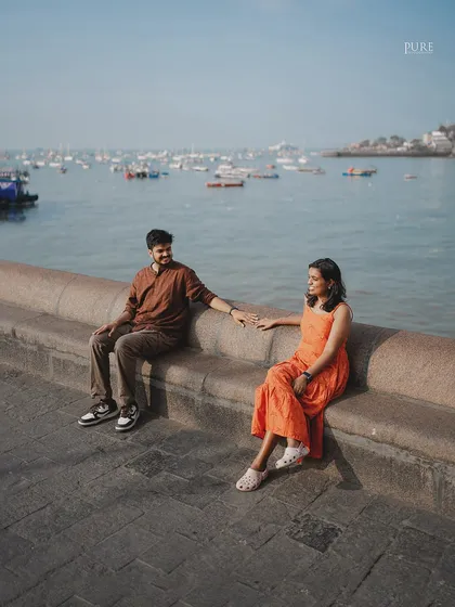 Nikit and Anusha share a quiet moment sitting on the sea wall at the Gateway of India, with the harbor and its many boats creating a classic Mumbai seascape behind them.