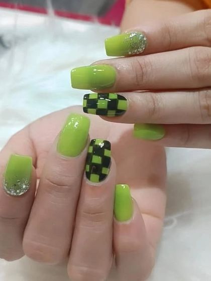 A bold lime green manicure with a black checkerboard pattern on the accent nails, finished with a touch of glitter.