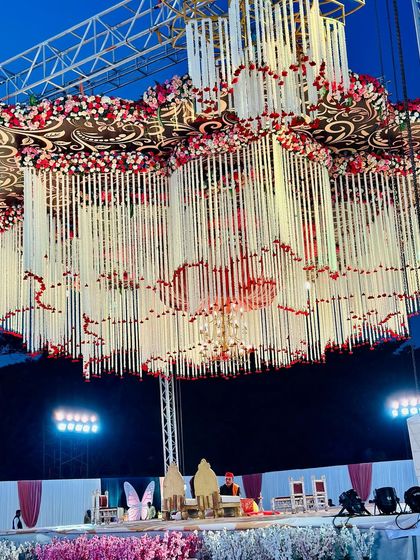 A view of our massive, multi-layered floral chandelier structure suspended over the main stage. The scale of this installation creates a powerful visual impact for a grand wedding.