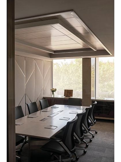 A meeting room in 'The Layered Office' featuring a custom ceiling detail and geometric fabric wall paneling. The design is consistent across all meeting rooms in the building to provide a uniform experience for all three resident companies.