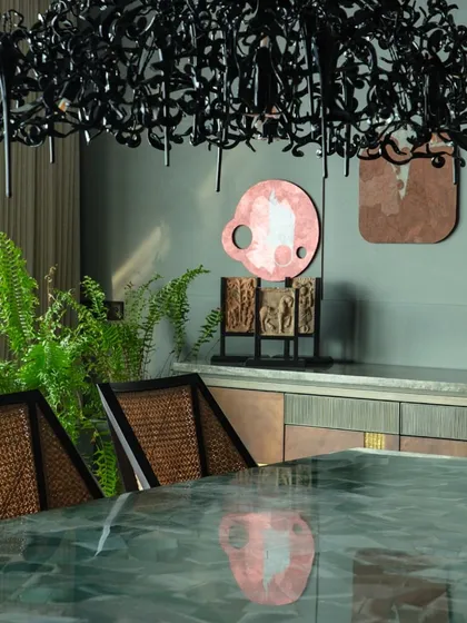 Detail of the dining room, highlighting the green aventurine table and the dramatic black chandelier. The artwork by Tanmoy Samanta adds a layer of contemporary abstraction.