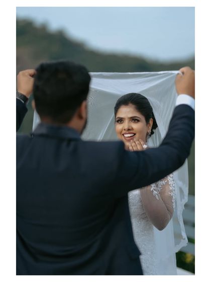 A playful and sweet interaction as the groom lifts the bride's veil. This candid photo captures the fun and romance of the couple's relationship.