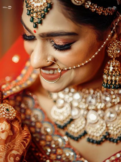 A detailed close-up of the bride's face, focusing on her intricate jewelry and beautiful smile. This shot highlights the opulence of the bridal look.
