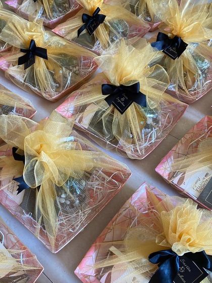 These beautifully wrapped return favours were created for a 25th anniversary celebration. The gift trays are wrapped in gold tulle with black ribbons, creating a look of classic elegance.