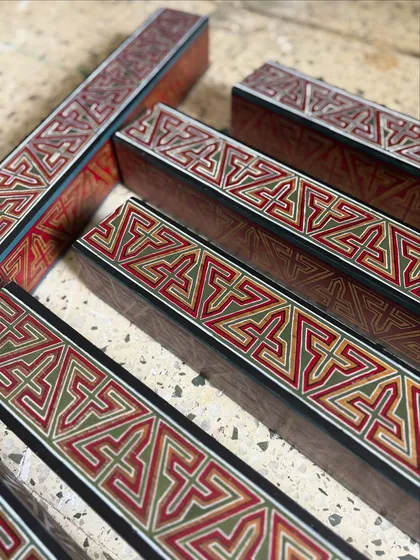 A collection of the hand-painted wooden rafters before installation. This shot highlights the detailed craftsmanship and the rich, warm color palette of the geometric Arabic patterns.
