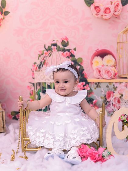 This adorable toddler is all smiles in our pink floral room, sitting on a tiny golden bed. The intricate details and soft colors make this a truly royal setup.