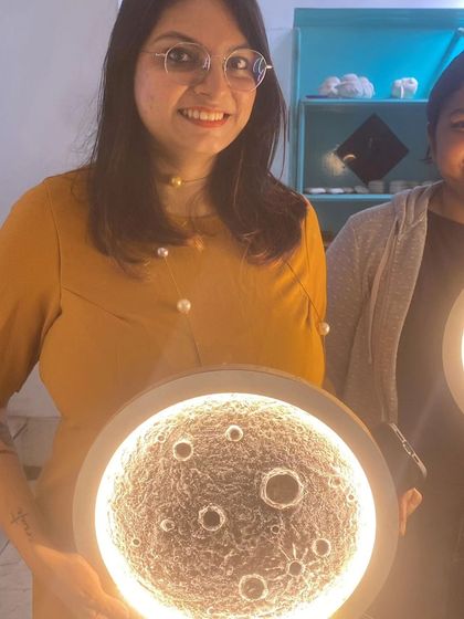 A participant from our moon lamp workshop, happy with the celestial artwork she created. These lamps make for a unique and personal home decor item.