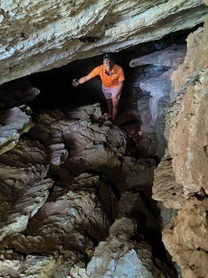 A trekker with a headlamp exploring the dark and narrow passages of the Ulavi caves.