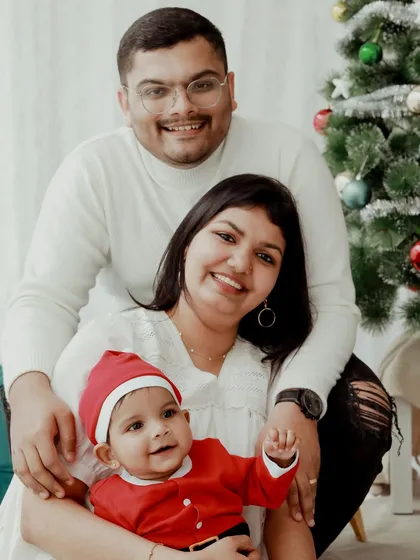 A happy family enjoying their baby's first Christmas. Their bright smiles and the festive Santa hat on the little one make this a joyful portrait.