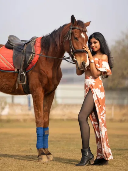 A stylish pose with the model standing next to the horse, showcasing both the fashion and the majestic animal.