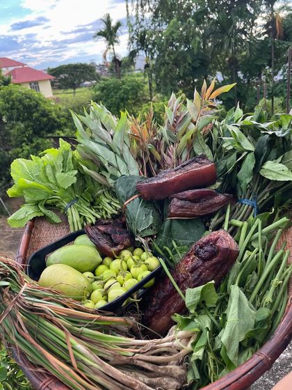 A basket overflowing with a fresh harvest from Nagaland. It contains smoked pork, wild greens, and local fruits, ready to be used in our kitchen.