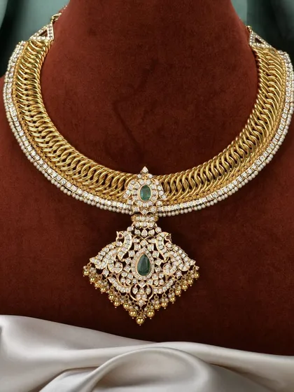 The best of both worlds. This is our stunning gold-plated silver sutarla necklace, featuring an intricate woven design and a grand pendant with emerald and polki-style stones. It gives you the opulent look of gold with the purity of silver.