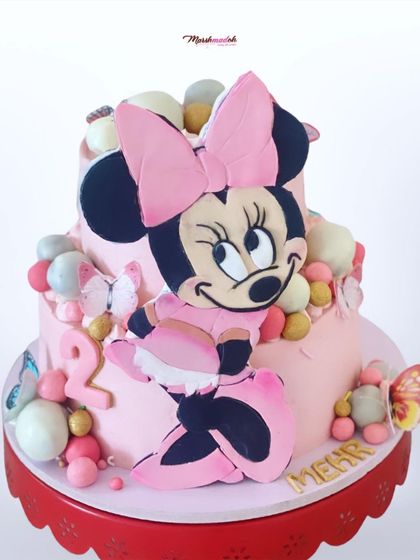 A slightly different angle of the grand Minnie Mouse cake, showing more of the cake pops and the name "Mehr" in gold lettering.