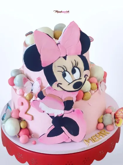 A slightly different angle of the grand Minnie Mouse cake, showing more of the cake pops and the name "Mehr" in gold lettering.