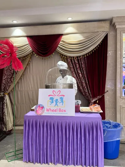 A wider view of our simple and professional table setup for a cotton candy station at an indoor event, showing our branded sign and equipment.