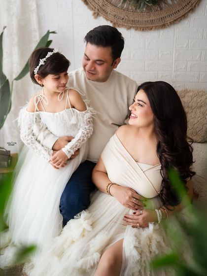 A family portrait filled with gentle looks and loving touches. The parents and their daughter share a sweet moment, with the mother's pregnancy adding to the feeling of anticipation.