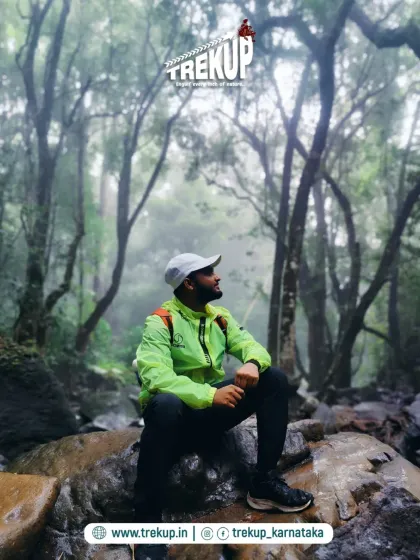 A trekker pausing for a moment of quiet reflection in the misty forests of the Netravathi trail.
