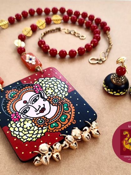 Inspired by the auspicious energy of Vellikayamai (Friday), this necklace set is dedicated to Goddess Lakshmi. The hand-painted pendant is adorned with malargal (flowers) and paired with wooden jhumkas, glass beads, and brass ghungroos.