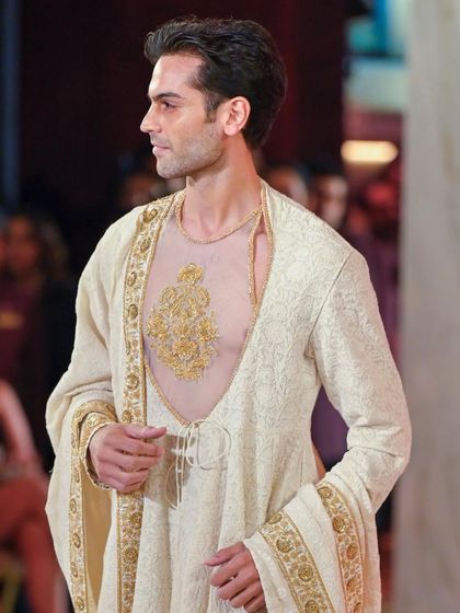 Male grooming for the Abu Jani Sandeep Khosla show. This look is clean and refined, focusing on flawless skin and subtly defined features to complement the regal, embroidered outfit.