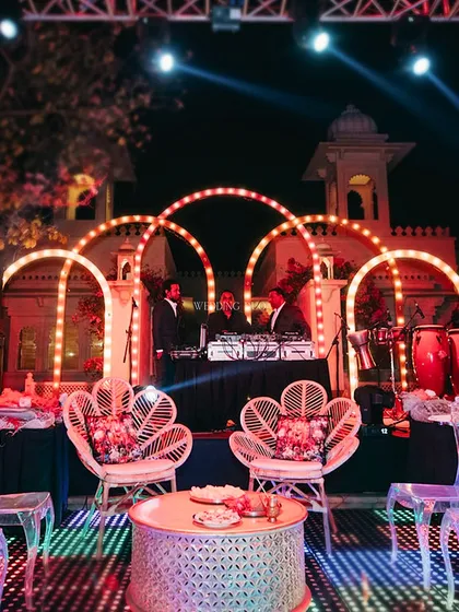The DJ setup was framed by glowing arches, with an LED dance floor ready for the party. The mix of modern lighting and bohemian peacock chairs created a unique, eclectic vibe.