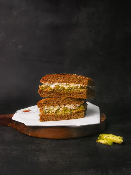 A stacked multigrain sandwich, shot against a textured dark background. This style is great for cafes wanting to project a modern and artisanal image.