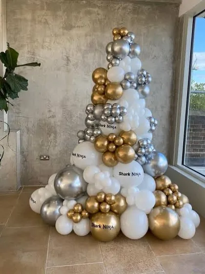 For a modern take on Christmas, I can build a custom balloon Christmas tree like this one. This installation uses a mix of white, chrome silver, and gold balloons in various sizes to create a stylish, festive structure that's perfect for corporate lobbies or contemporary homes.