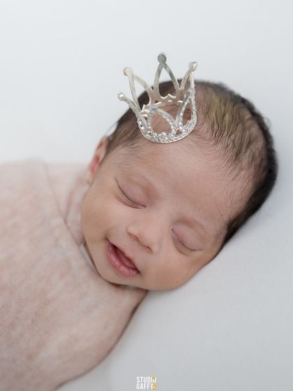 Every baby is a prince or princess. This sweet newborn smiles in their sleep while wearing a tiny, sparkling crown.