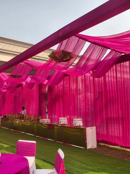 The catering area at a Haldi function, decorated with pink fabric draping to match the event's color scheme.