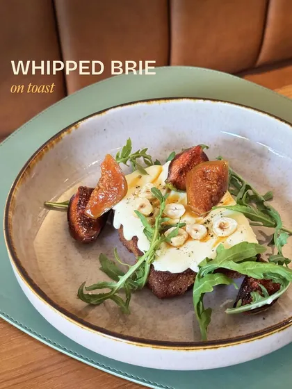 Our Whipped Brie on Toast, a simple yet elegant dish with creamy brie, sweet macerated figs, and crunchy hazelnuts on sourdough.