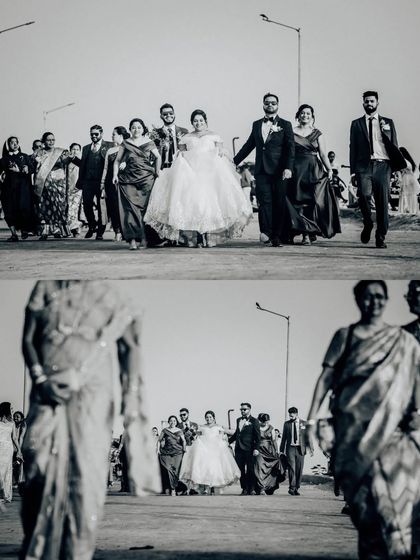 A wide shot of the wedding procession, using foreground elements to frame the couple. This black and white photo has great depth and composition.