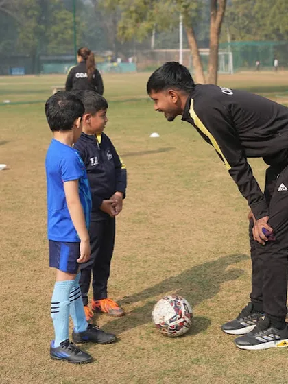 The power of one-on-one attention. A coach connects with young players, providing personalized feedback and encouragement, which is a key part of our training methodology.