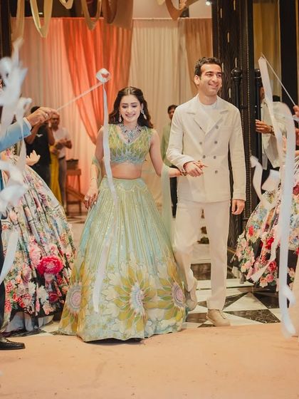 The couple makes their way through the ribbon-lined aisle, smiling and holding hands in a moment of effortless celebration.