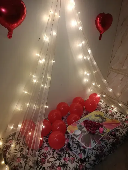 A closer look at the fairy light canopy, showing how the sheer fabric and warm lights create a soft, glowing effect. Red balloons are placed inside and around the seating area.